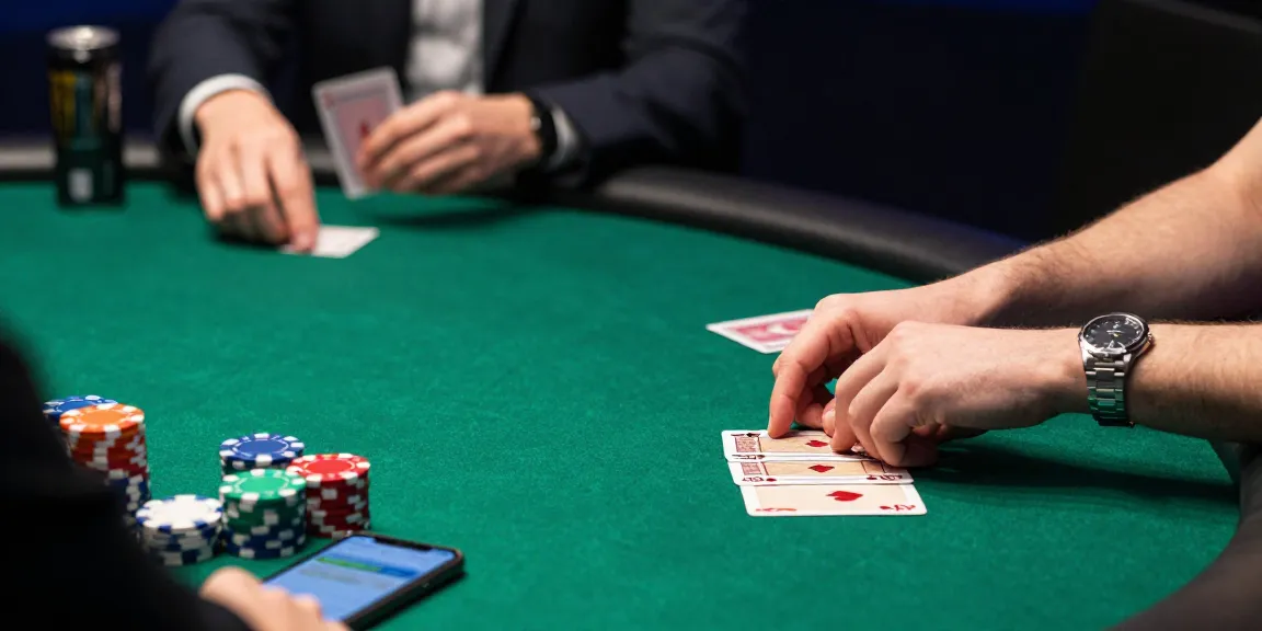 Engaged player at poker table examining cards, illustrating rajakhodam89 daftar excitement in a vibrant gambling setting.